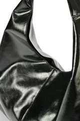 Cartera tipo slouchy color negro, confeccionada en 100% poliuretano simil cuero, con diseño amplio y asa de hombro integrada.