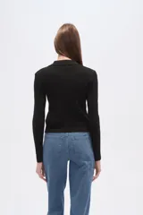 Saco de tejido de punto acanalado, color negro, con cuello tipo camisa y cierre frontal completo. De corte ajustado al cuerpo y manga larga.