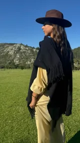 Ruana de lana merino en color tostado, con diseño de punto texturizado y terminación de flecos en el ruedo.