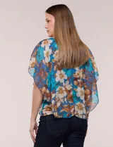 Blusa de gasa semitransparente con hilos de lúrex, diseño estampado floral en tonos blanco, gris y negro, silueta holgada tipo capa y escote redondo con detalle metálico.