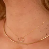 Conjunto de joyería en oro 18k compuesto por una cadena fina con dije ovalado engastado con brillantes y una gargantilla rígida minimalista.