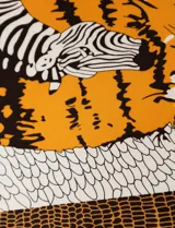 Pashmina cuadrada de satén estampado en tonos naranja, blanco y negro, con diseño de escamas.