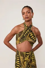 Top negro con estampado de hojas amarillas, escote halter cruzado, corte ajustado y lazo regulable en la espalda.