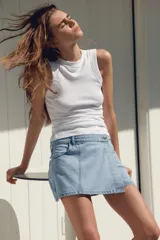 Falda pantalón corta de tiro alto confeccionada en denim celeste. Presenta bolsillos delanteros y traseros. Cierre frontal cruzado con cremallera oculta y botón metálico.