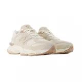 Championes New Balance modelo 9060, con diseño robusto y moderno en tonos beige y crema. Presentan una combinación de texturas en gamuza y malla, con la característica letra N en los laterales y una suela voluminosa con tecnología de amortiguación.