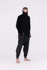 Sweater negro de tejido de punto, con cuello tortuga que se puede usar como pasamontañas, mangas largas con abertura para el dedo y roturas verticales en el frente.