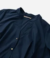 Vestido chemise midi de corte holgado, confeccionado en tricolina color azul marino. Presenta cuello tipo padre, cierre frontal con botones metalizados, mangas cortas y pliegues en la falda. Incluye un cinturón marrón para ajustar a la cintura.