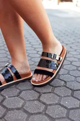 Sandalias bajas de cuero color marrón con tiras de cuero charol negro y hebilla metálica.