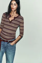 Jersey de punto fino con diseño a rayas horizontales en tonos tierra, bordó y celeste. Presenta cuello redondo, cierre frontal con botones y mangas por debajo del codo.