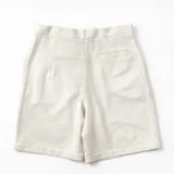 Bermuda de algodón y lino en color blanco, de tiro medio y calce relajado. Presenta un diseño minimalista con cierre frontal de botones y ganchito oculto en la cintura, además de prácticos bolsillos laterales.