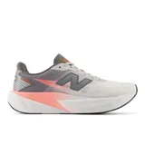 Championes de running New Balance FuelCell Rebel v5, color gris con detalles en naranja y suela blanca.