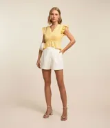 Blusa amarilla sin mangas confeccionada en laise con cuello V, volados en los hombros y recorte fruncido en la cintura.