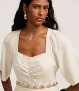 Mono largo color crudo, de corte wide leg, con escote cuadrado, fruncido en el busto, mangas cortas con pliegues en las sisas y cierre por cremallera en la espalda. Confeccionado en tejido viscolino.