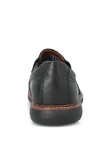 Zapato tipo mocasín Hush Puppies modelo Oregon, confeccionado en cuero negro con textura granulada. Presenta un diseño slip-on con elásticos laterales, costuras reforzadas y una suela de goma EVA que proporciona flexibilidad y aislamiento térmico.