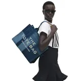 Bolso tipo tote de Marc Jacobs confeccionado en denim azul con diseño de paneles en diferentes tonos. Presenta el logo 'THE TOTE BAG' estampado en la parte frontal y doble asa superior.