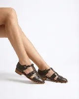 Zapato tipo cangrejera de cuero color marrón, con diseño de tiras entrelazadas, punta cerrada y pulsera con hebilla ajustable al tobillo. Cuenta con un taco bajo de madera.