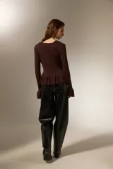 Top de punto color marrón, con cuello redondo amplio, cierre frontal con botones, mangas largas con puños acampanados y detalle de volados en el cuello y el ruedo.