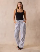 Pantalón cargo de lino a rayas verticales grises y blancas, marca Marissa Olivia. Pretina ancha elastizada con lazo de ajuste, bolsillos inclinados delanteros y bolsillos laterales con botón.