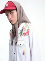 Triángulo tipo capucha con lazo, confeccionado en tejido de punto suave. Presenta un diseño versátil que puede usarse como pañuelo o accesorio para la cabeza.