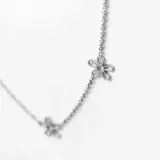 Collar plateado con cadena de eslabones y dijes de margaritas caladas.