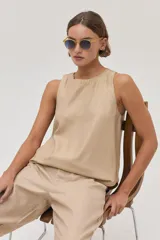 Conjunto color beige compuesto por un top sin mangas y un pantalón chino de lino metalizado, con tiro medio-alto, pierna recta, bolsillos laterales y traseros.