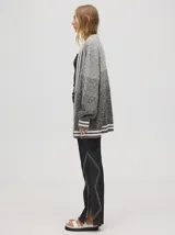 Cardigan oversize de algodón con diseño tejido a rombos en tonos degradados de marrón y blanco. Presenta cuello en V, cierre frontal con botones de madera y puños y dobladillo con rayas blancas.