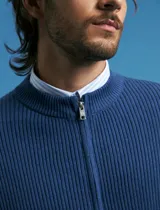 Cardigan de tejido de punto con cierre frontal completo, cuello redondo y bolsillos laterales. Presenta un diseño de textura acanalada y puños elásticos.