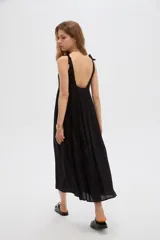 Vestido midi negro de viscosa con cuello cuadrado y tirantes finos ajustables con lazo en los hombros, de corte holgado y diseño fluido.