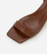 Sandalias negras de cuero sintético, con punta cuadrada, tira fina sobre los dedos, pulsera con hebilla al tobillo y tacón geométrico bajo.