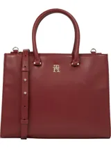 Cartera tote de Tommy Hilfiger color borgoña, con doble asa de mano y correa larga extraíble y ajustable. Tiene cierre magnético, dos compartimentos principales y tres bolsillos interiores con cremallera.