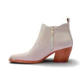 Bota texana de caña corta en color beige, con diseño de elásticos laterales, taco cuadrado de madera y puntera metálica decorativa.