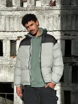 Campera puffer gris con sección superior negra y cierre frontal.