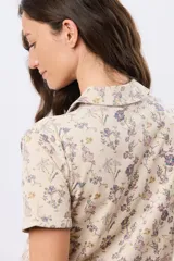 Camisa de algodón de manga corta en tejido jersey, con estampado floral de inspiración retro, cuello camisero y abertura frontal parcial con botones.