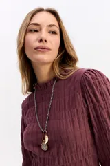 Blusa negra de algodón con textura fruncida en todo el cuerpo, cuello alto y puños con volados.