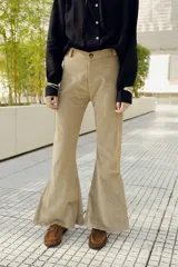 Pantalón de corderoy color beige, tiro alto, corte ajustado en muslos y campana marcada en la parte inferior.