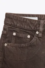 Jeans de tiro alto con corte mom fit, cinco bolsillos y cierre frontal con cremallera y botón metálico.
