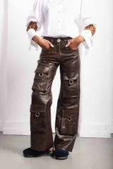Pantalón cargo de tiro medio y silueta recta amplia, color marrón con efecto óxido. Cuenta con cierre frontal, botón, bolsillos delanteros clásicos y múltiples bolsillos cargo con solapa y herrajes metálicos.