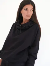 Buzo negro oversize de felpa con capucha y espalda descubierta, mangas largas, calce relajado y detalle de logo bordado en la parte inferior.