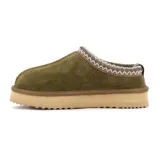 Pantufla tipo zueco de cuero gamuzado color verde oliva, con interior de peluche y suela de plataforma de goma color beige. Presenta un detalle de costura decorativa trenzada en el borde superior.