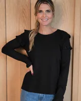 Remera de algodón color negro, con cuello redondo, manga larga y detalle de volados en los hombros.