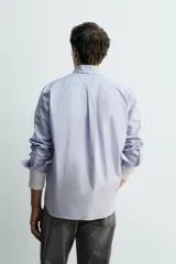 Camisa de corte relajado confeccionada en tejido de algodón con estampado de cuadros pequeños. Presenta cuello abotonado, cierre frontal con botones y manga larga con puños abotonados.