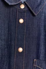 Camisa amplia de denim azul oscuro con cuello solapa, manga larga, bolsillo de plastrón en el pecho y cierre frontal con botones a presión dorados.