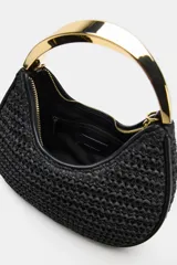 Bolso de mano mini en color negro con cuerpo trenzado y un asa rígida metálica dorada, además de una correa bandolera extraíble.