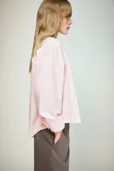 Camisa de popelín color rosa pálido, con cuello solapa, escote pico y manga larga terminada en puño. Cierre frontal con botones.