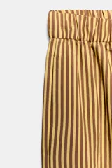 Pantalón de tiro medio con pierna ancha y cintura elástica, confeccionado en mezcla de viscosa con diseño de rayas verticales en tonos mostaza y marrón.