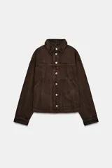 Cazadora de denim color marrón con cuello solapa, manga larga y cierre frontal con botones metálicos. Presenta dos bolsillos de plastrón en el delantero.