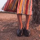 Zapato plano de cuero color marrón oscuro, con punta cuadrada, diseño escotado en V y detalle de medio cierre frontal a lo largo de la capellada.