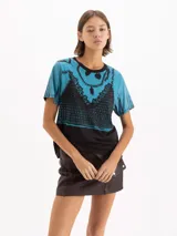 Remera de manga corta con cuello redondo, en tonos celeste y negro, con estampado frontal simulando un corset de encaje y collares de cadenas.