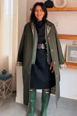 Vestido corto de corte recto y mangas cortas, confeccionado en tela lisa. Incluye un cinturón decorativo de cuero con ojales metálicos circulares que se repiten en todo su diseño.
