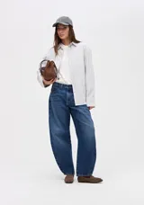 Jean de tiro alto con silueta tipo globo, ajustado en la cintura y con piernas holgadas que se estrechan hacia el bajo.